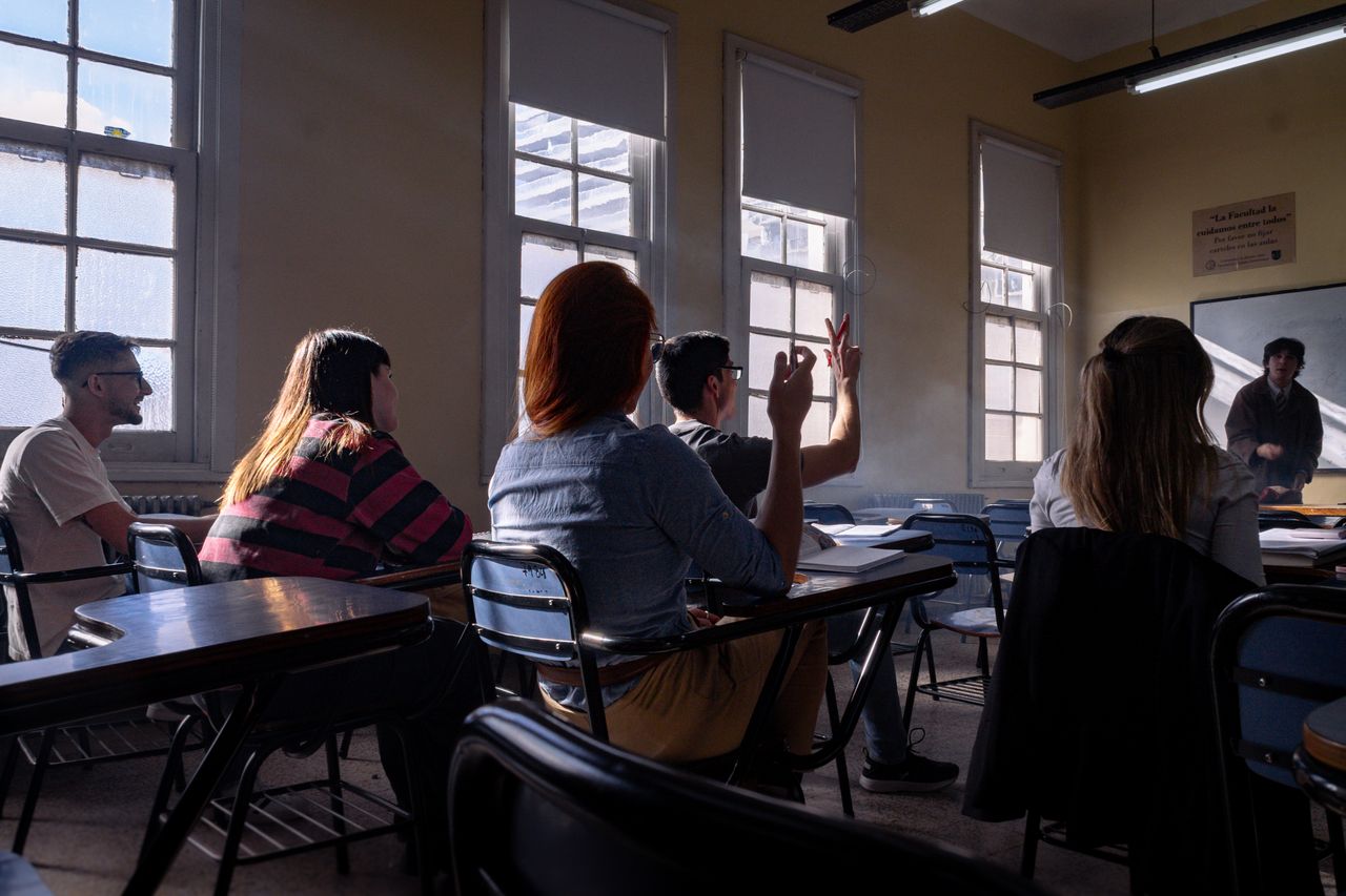 Estudiantes de secundaria trabajando con sensores y una estructura CANSAT en un laboratorio escolar.