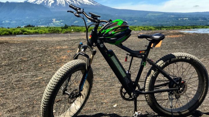 Ciclistas con alforjas recorriendo una ruta escénica entre montañas y bosque patagónico.