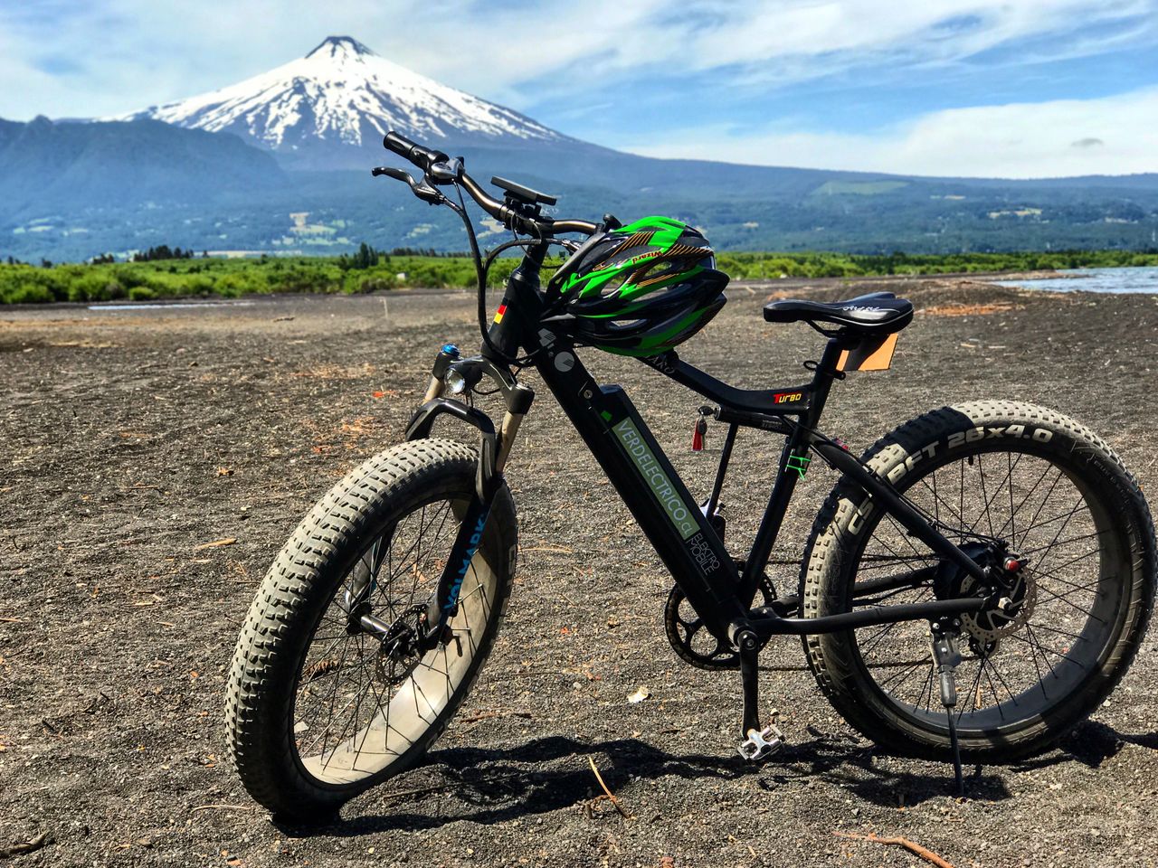 Ciclistas con alforjas recorriendo una ruta escénica entre montañas y bosque patagónico.